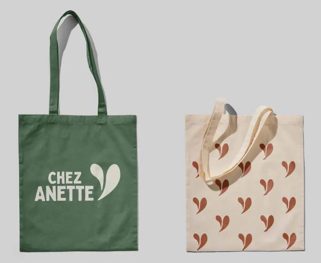 Deux sacs de tissu : l’un vert avec le logo Chez Anette, l’autre à motif de petits cœurs.